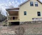 Newly constructed residential deck with pressure-treated framing and composite decking attached to yellow house