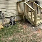 Pressure-treated wood deck with railings and stairs attached to residential home