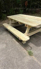 Pressure-treated wood picnic table with attached benches on concrete surface