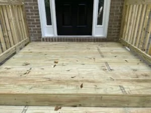 Pressure-treated wood deck frame with joists and beams, brick house exterior