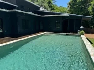 Composite pool deck with new boards surrounding turquoise pool and dark covered structure