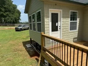 Newly constructed wooden front porch deck with black balusters and pressure-treated framing