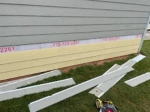 Vinyl soffit and aluminum fascia boards installed along residential roofline with staging materials on lawn
