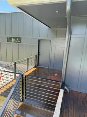 Dark-stained deck with cable railing, white painted soffit, and horizontal wood decking