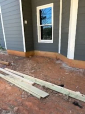 Pressure-treated deck framing and beams on gravel foundation against home exterior