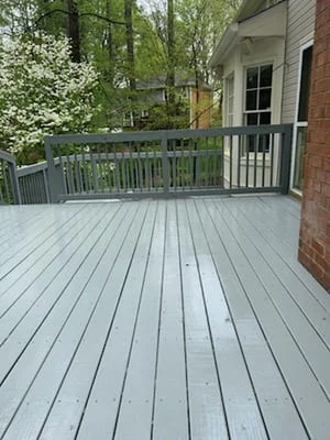 Gray painted composite deck with matching railings and brick house exterior