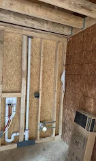 Interior wall framing with wooden studs, horizontal blocking, and staged drywall sheets