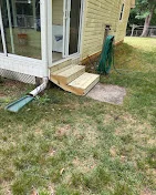Wooden deck entry steps with pressure-treated lumber construction installed at ground level