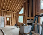 Interior carpentry with wood-framed vaulted ceiling, wall paneling, and structural framing