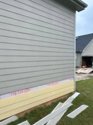 Gray horizontal lap siding installation on house exterior with house wrap and staging boards