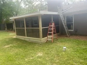 Screened porch with wood framing, vertical screens, and pitched roof under construction