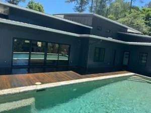 Composite deck with wood-tone boards adjacent to dark exterior home with large windows