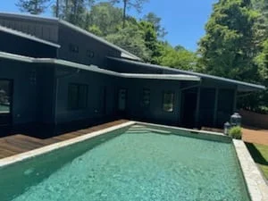 Composite pool deck with integrated seating, modern dark-clad pool house, and clear turquoise pool water