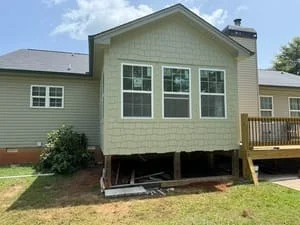 Elevated home addition with new siding, windows, and pressure-treated deck framing