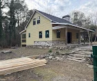Yellow-sided house with new siding, roofing, and framing work in progress