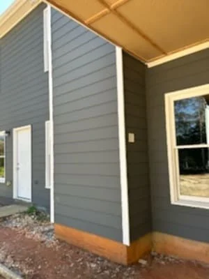 Gray horizontal siding with white trim and window frame on home exterior