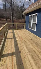 Newly constructed pressure-treated wood deck with railing and linear board pattern