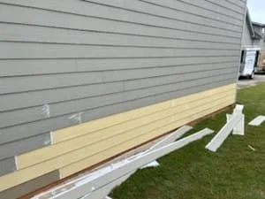 Pressure-treated deck frame with support posts and concrete footings along house foundation