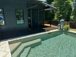 Green-stained composite deck with dark-painted exterior structure and manicured landscaping