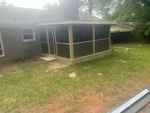 Screened porch with wooden framing, screen panels, and pitched roof attached to home