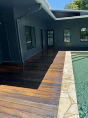 Charcoal gray painted house exterior with medium-toned stained hardwood deck and stone border