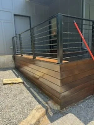 Stained wood deck with black metal horizontal railing and balusters