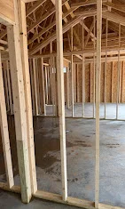 Interior framing with wooden studs and installed drywall in open room space