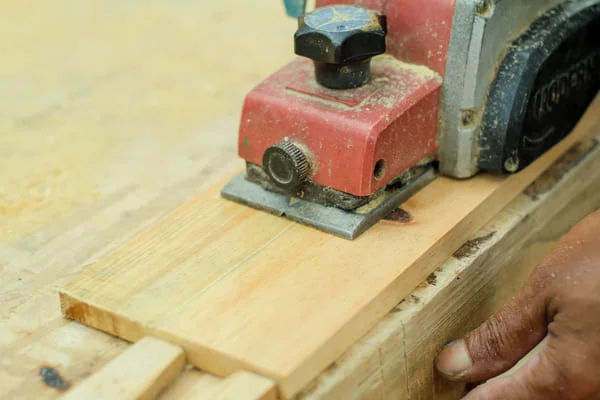 Red orbital floor sander on light wood flooring during sanding preparation