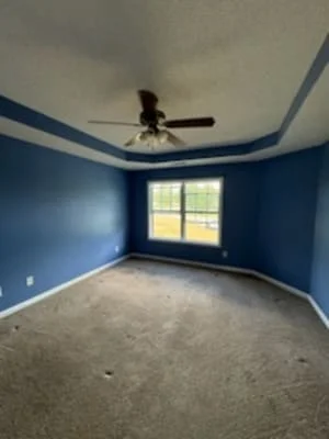 Bedroom with deep blue walls, white ceiling trim, and ceiling fan installation